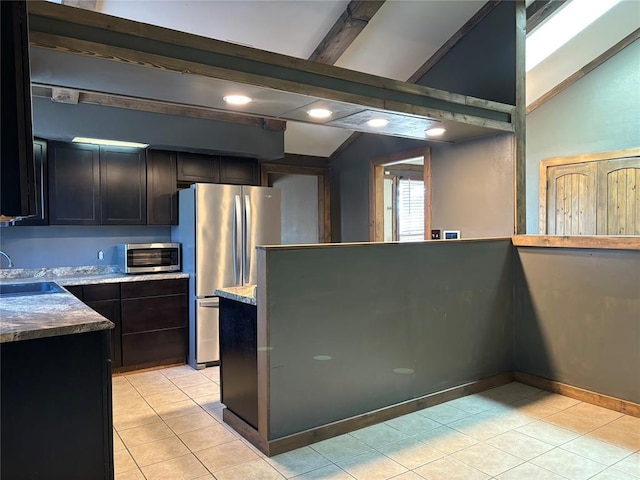 kitchen with vaulted ceiling with beams, sink, stainless steel refrigerator, and light tile patterned floors