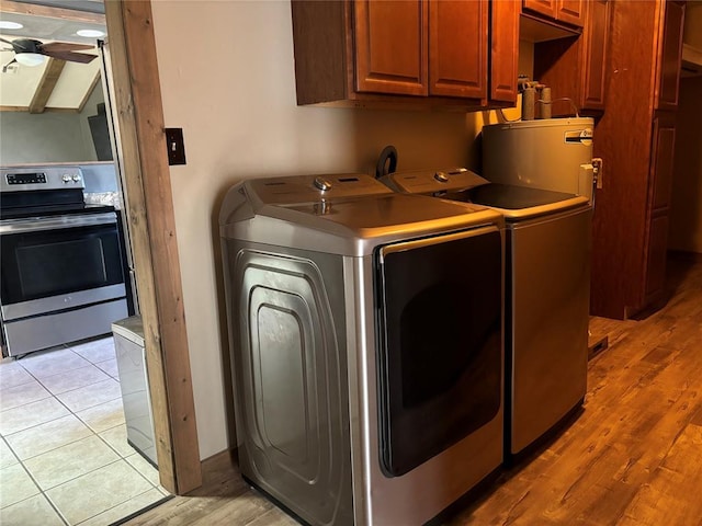 laundry area with water heater, light tile patterned floors, ceiling fan, washer and dryer, and cabinets