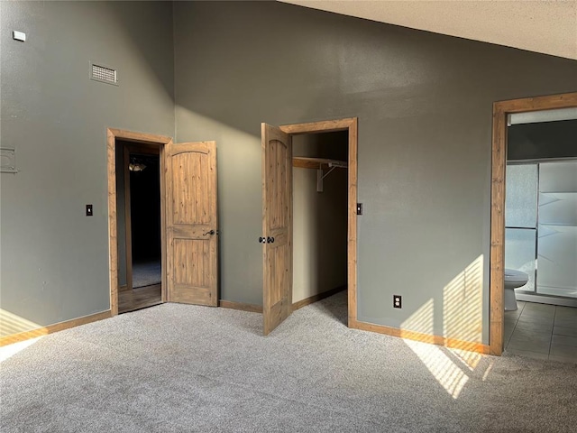 unfurnished bedroom featuring connected bathroom, a closet, a walk in closet, and carpet flooring