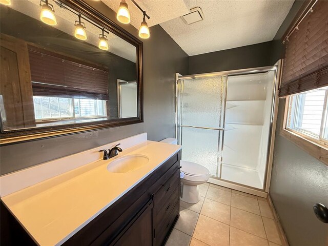 bathroom featuring a textured ceiling, tile patterned floors, vanity, toilet, and walk in shower