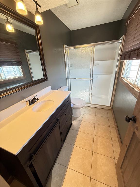 bathroom with toilet, tile patterned floors, walk in shower, a textured ceiling, and vanity