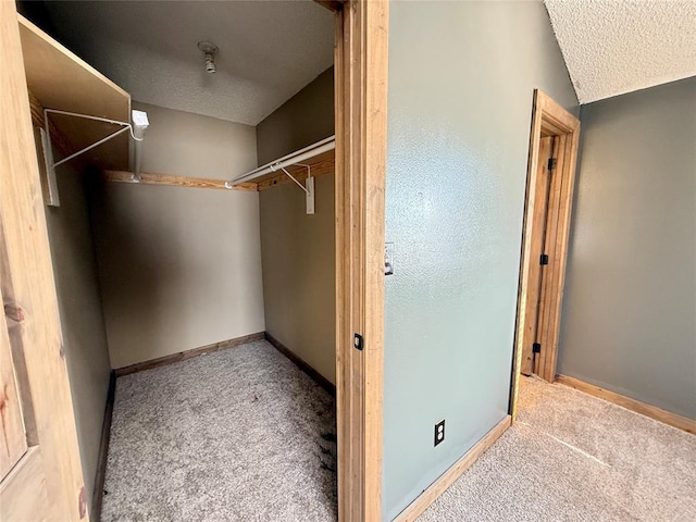 spacious closet featuring light colored carpet and vaulted ceiling