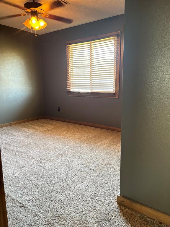 carpeted empty room featuring ceiling fan and a textured ceiling