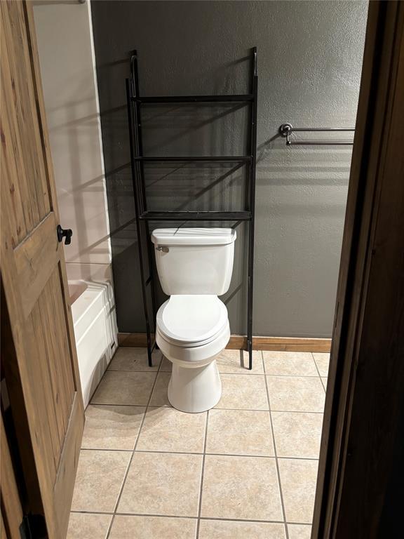 bathroom with a tub, toilet, and tile patterned flooring