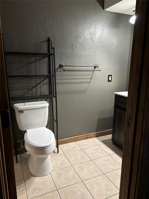 bathroom with a textured ceiling, tile patterned floors, vanity, and toilet