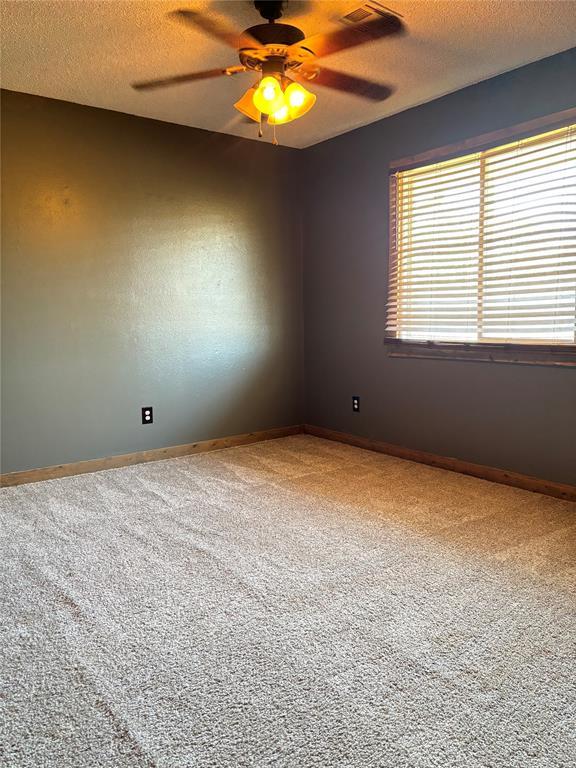 unfurnished room featuring a textured ceiling, ceiling fan, and carpet flooring