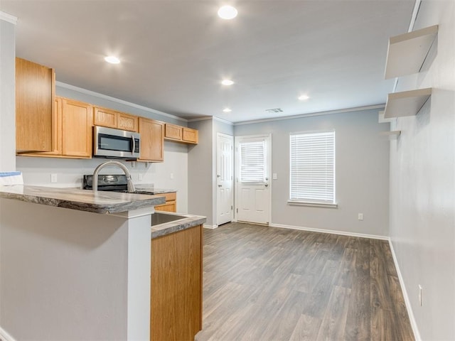 kitchen featuring stainless steel appliances, dark hardwood / wood-style flooring, kitchen peninsula, a breakfast bar area, and ornamental molding