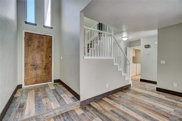 foyer entrance with hardwood / wood-style floors and washer and dryer