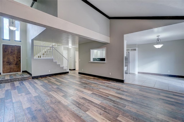 unfurnished living room featuring wood-type flooring and high vaulted ceiling