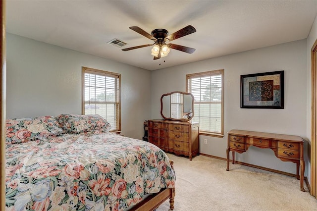 bedroom with multiple windows, light colored carpet, and ceiling fan