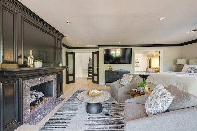 living room with crown molding, light hardwood / wood-style flooring, and a premium fireplace