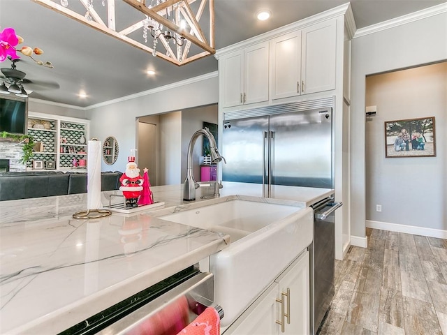 kitchen featuring white cabinets, crown molding, light hardwood / wood-style floors, light stone counters, and stainless steel appliances