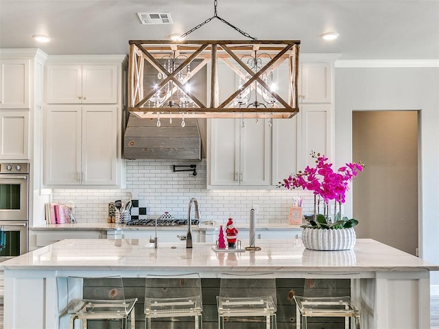 kitchen with light stone countertops, backsplash, and white cabinets