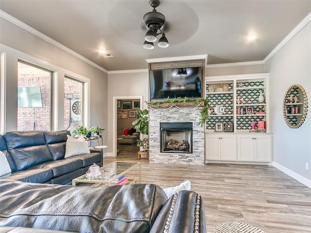 living area featuring crown molding, a stone fireplace, a ceiling fan, and wood finished floors