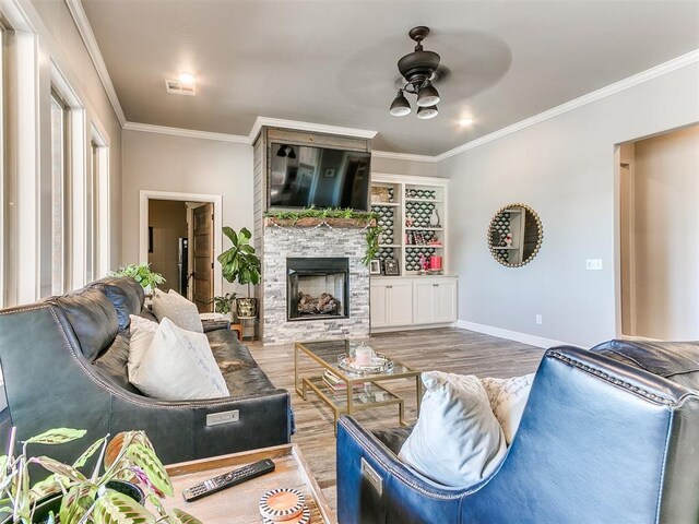 living area with crown molding, ceiling fan, baseboards, wood finished floors, and visible vents