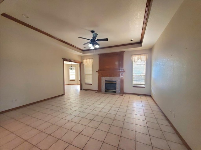 unfurnished living room featuring light tile patterned flooring, a raised ceiling, ceiling fan, ornamental molding, and a large fireplace