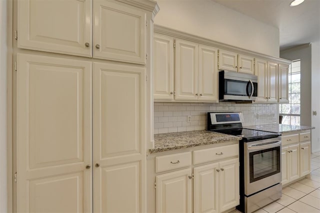 kitchen with backsplash, light stone counters, light tile patterned floors, and stainless steel appliances