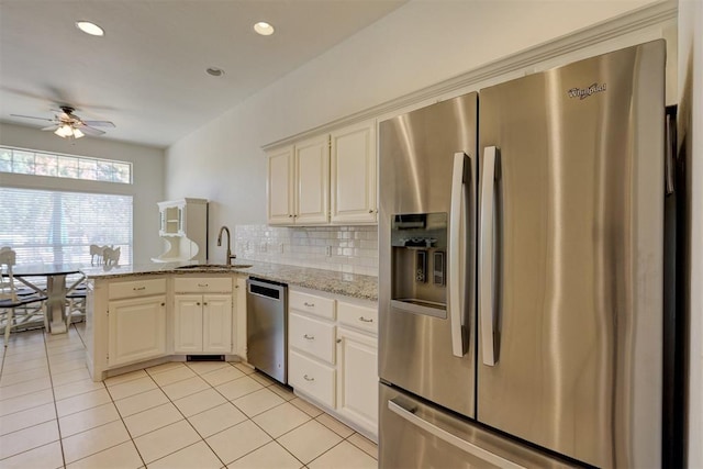 kitchen featuring light stone countertops, sink, ceiling fan, kitchen peninsula, and appliances with stainless steel finishes