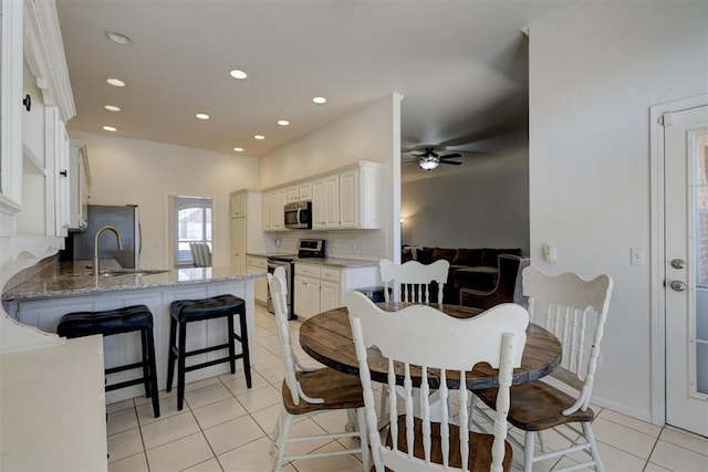 tiled dining area with ceiling fan and sink