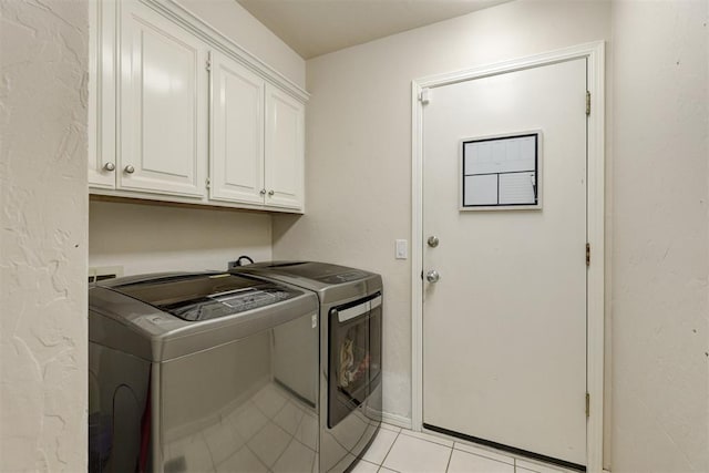 washroom featuring separate washer and dryer, light tile patterned flooring, and cabinets