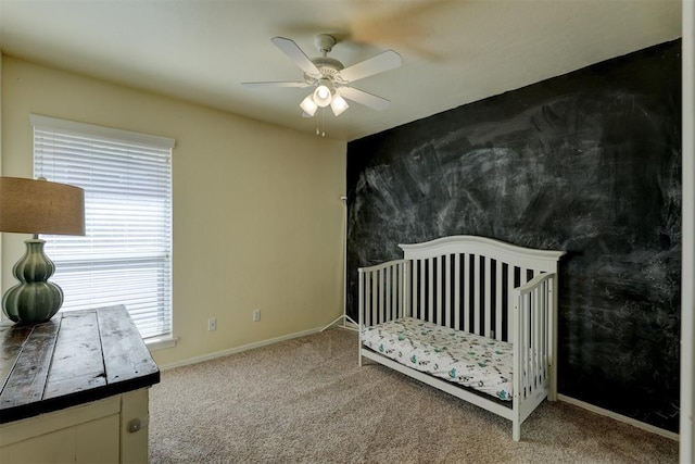 carpeted bedroom with ceiling fan and a crib