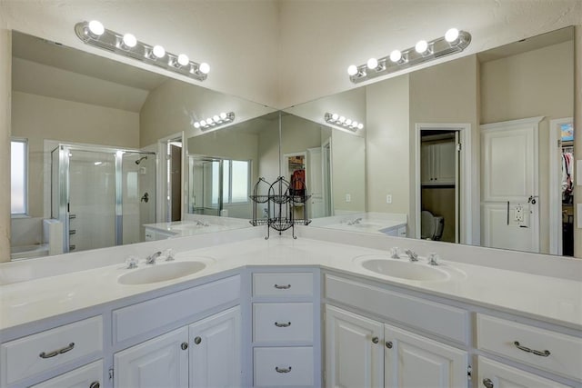 bathroom with a wealth of natural light, vanity, vaulted ceiling, and an enclosed shower