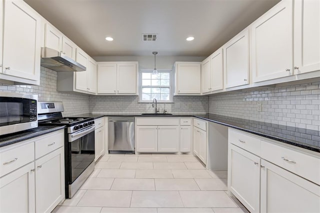 kitchen with pendant lighting, backsplash, sink, appliances with stainless steel finishes, and white cabinetry