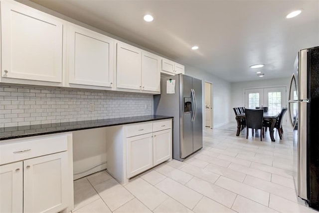 kitchen with white cabinetry, tasteful backsplash, stainless steel refrigerator with ice dispenser, dark stone countertops, and stainless steel fridge