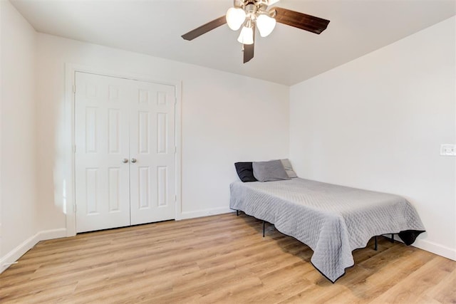 bedroom with a closet, light hardwood / wood-style floors, and ceiling fan