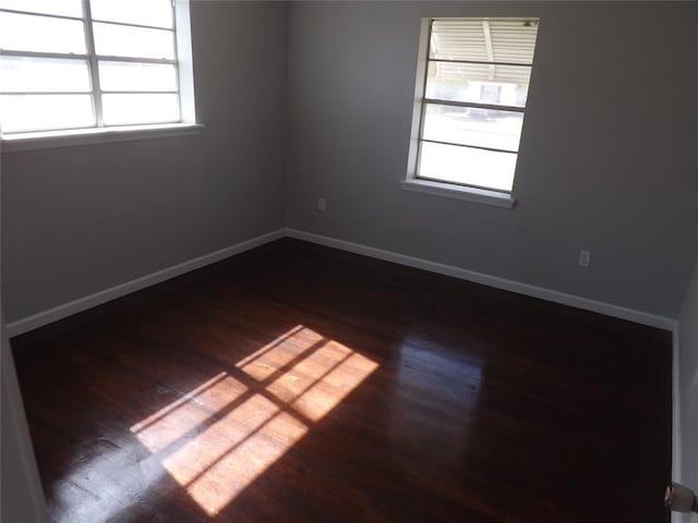 spare room with plenty of natural light and dark hardwood / wood-style flooring