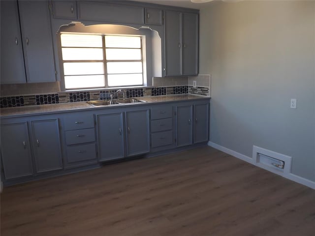 kitchen with backsplash, gray cabinets, sink, and dark hardwood / wood-style flooring