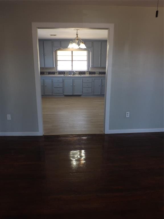 interior space featuring sink, pendant lighting, an inviting chandelier, gray cabinets, and dark hardwood / wood-style floors