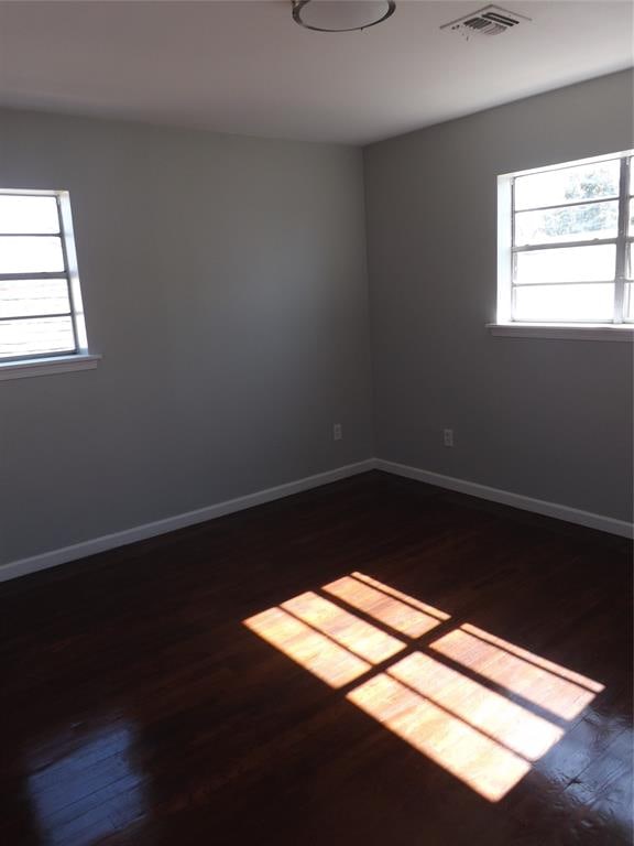 unfurnished room featuring dark hardwood / wood-style flooring and a healthy amount of sunlight