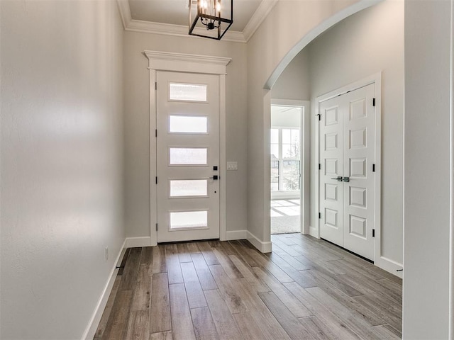 foyer entrance with a notable chandelier, light hardwood / wood-style floors, and crown molding