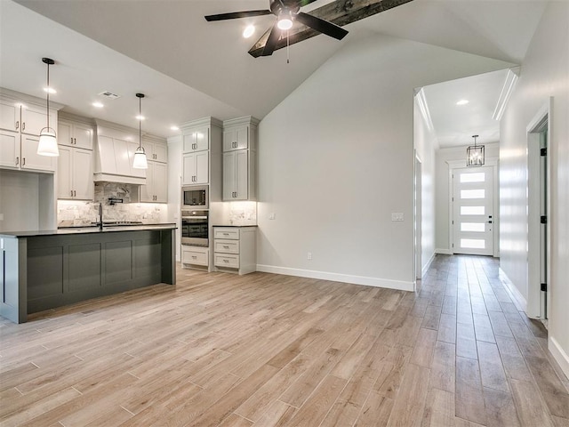 kitchen featuring decorative light fixtures, lofted ceiling with beams, appliances with stainless steel finishes, and light hardwood / wood-style flooring