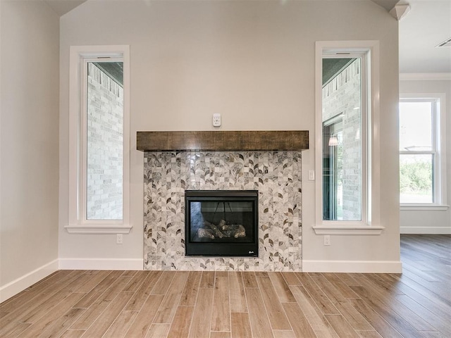 unfurnished living room featuring wood-type flooring, crown molding, and a tile fireplace