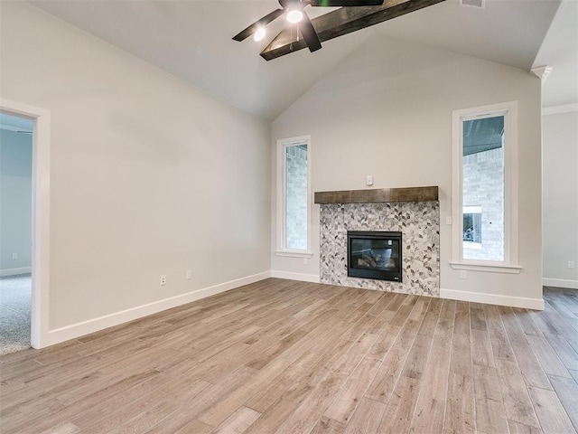 unfurnished living room featuring light wood-type flooring, a fireplace, a wealth of natural light, and vaulted ceiling