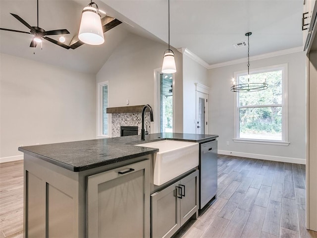 kitchen with a kitchen island with sink, ceiling fan with notable chandelier, sink, stainless steel dishwasher, and light hardwood / wood-style floors