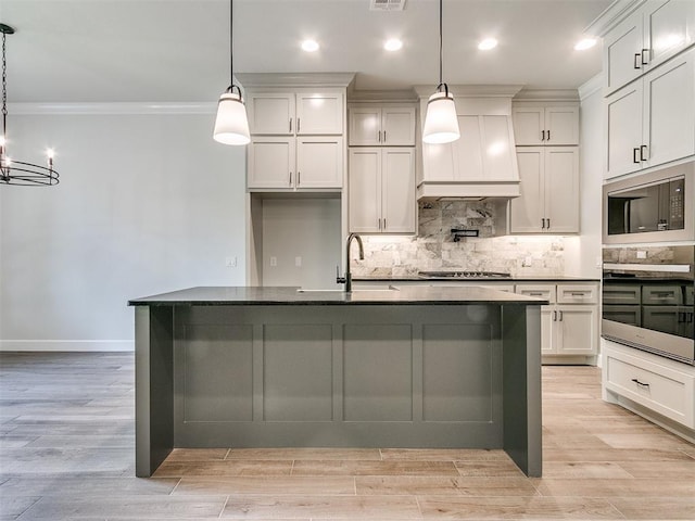 kitchen featuring a kitchen island with sink, hanging light fixtures, stainless steel appliances, and sink