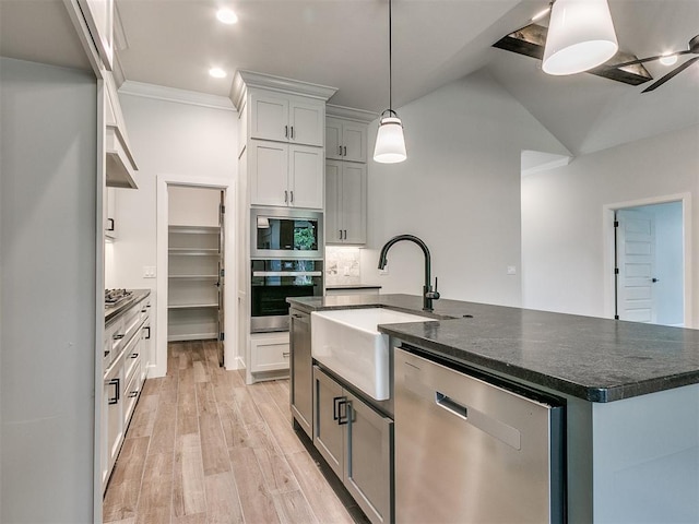 kitchen featuring sink, decorative backsplash, an island with sink, appliances with stainless steel finishes, and light hardwood / wood-style floors