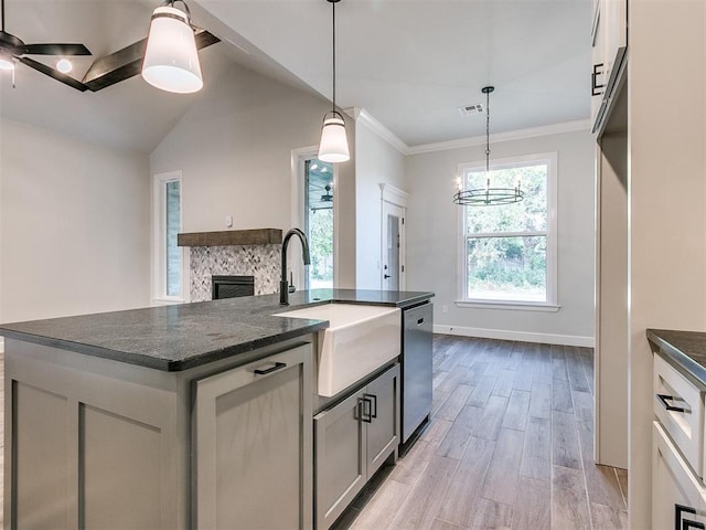 kitchen with ceiling fan with notable chandelier, a kitchen island with sink, light hardwood / wood-style flooring, dishwasher, and hanging light fixtures