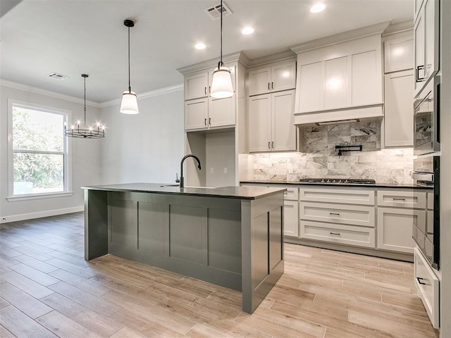 kitchen featuring exhaust hood, an island with sink, pendant lighting, and light hardwood / wood-style floors