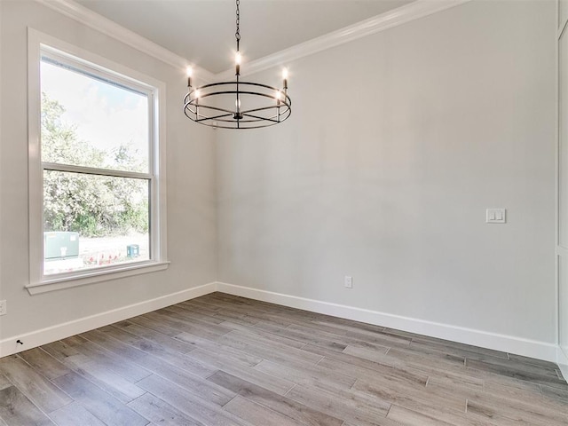 unfurnished dining area featuring a chandelier, crown molding, and light hardwood / wood-style floors