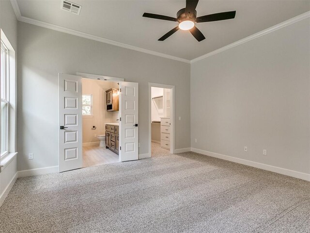 unfurnished bedroom with light carpet, a walk in closet, ensuite bathroom, ornamental molding, and ceiling fan