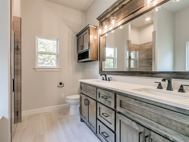 bathroom featuring walk in shower, vanity, toilet, and plenty of natural light