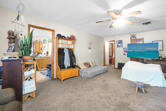 bedroom with ceiling fan, carpet, and a textured ceiling