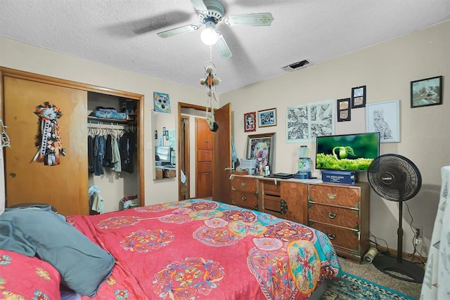 bedroom with carpet flooring, a textured ceiling, a closet, and ceiling fan