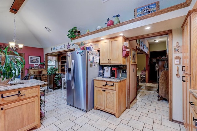 kitchen featuring stainless steel refrigerator with ice dispenser, lofted ceiling, light brown cabinetry, light stone counters, and pendant lighting