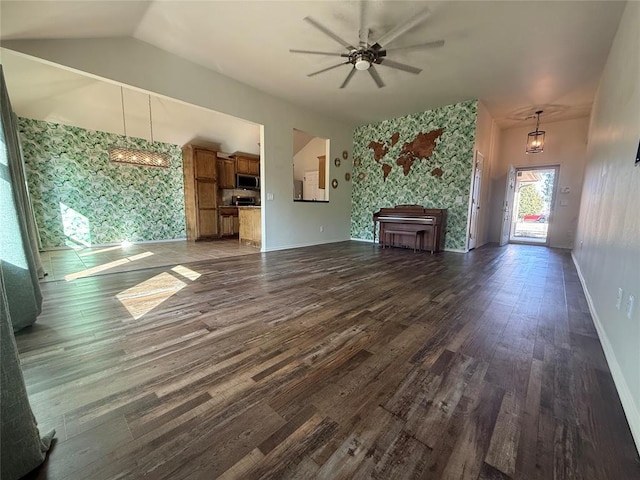 unfurnished living room with vaulted ceiling, dark wood-type flooring, and ceiling fan with notable chandelier