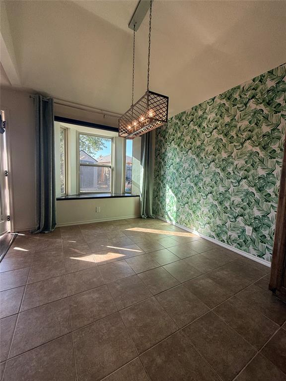 unfurnished dining area featuring dark tile patterned floors and vaulted ceiling